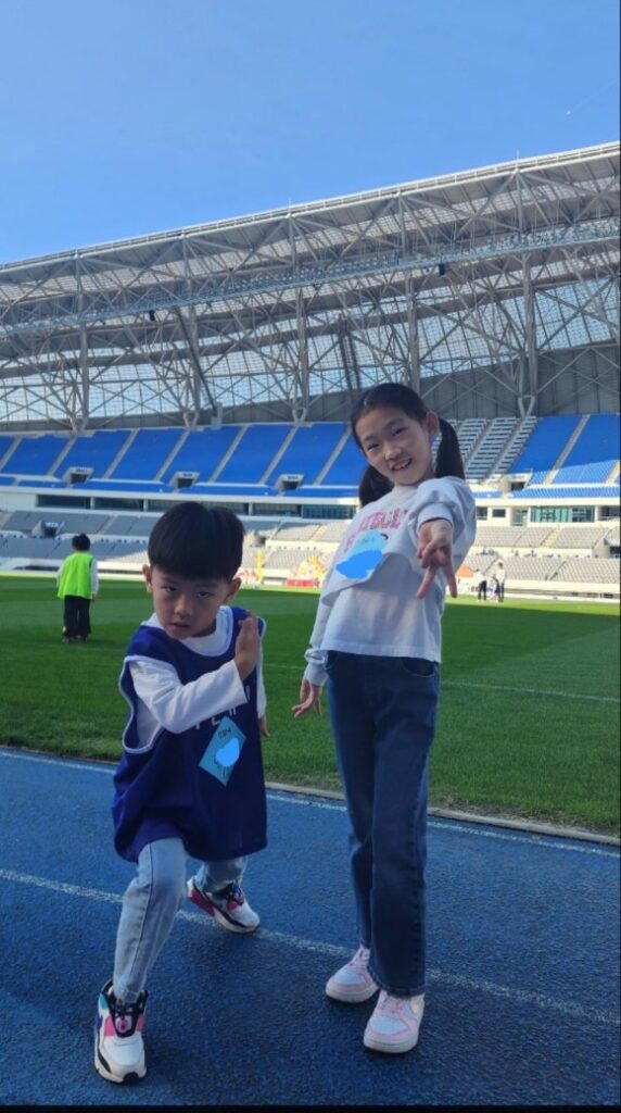 종합운동장 트랙에서 뛰어놀고 있는 어린이 두 명이 써 있습니다. 